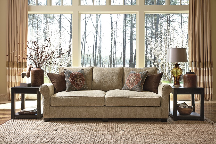 Brown cushioned sofa with Moroccan pillows on top with rustic background.