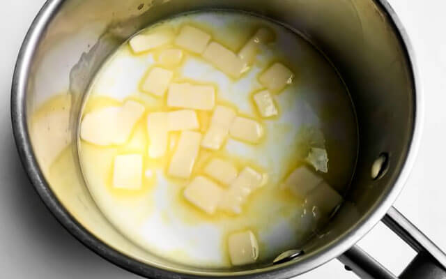 В сотейнике соединяем воду, молоко, порезанное кубиками сливочное масло и соль. Ставим на средний огонь. Размешиваем до полного растопления масла и доводим массу до кипения.